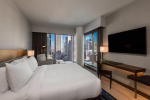 a hotel room with a large bed and a desk with a window at AC Hotel by Marriott Denver Downtown in Denver