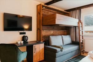 a bedroom with a bunk bed with a chair and a desk at Dorfhotel Glücksschmiede in Saalbach-Hinterglemm