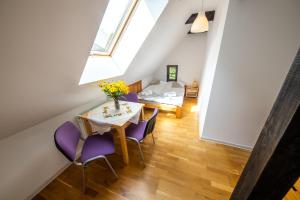 a attic dining room with a table and purple chairs at Żywkowo Bocianie Gospodarstwo Rolne in Górowo Iławeckie