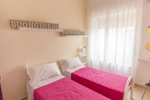 two beds in a room with pink sheets at BDREAMS APARTAMENT in Castellammare di Stabia