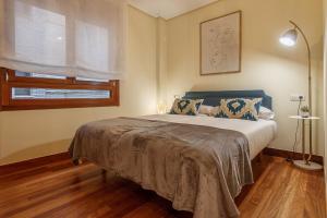 um quarto com uma cama com uma cabeceira azul e uma janela em Olabeaga apartamento urbano de diseño con wifi em Bilbao