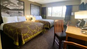 a hotel room with two beds and a desk at Super 8 by Wyndham Castlegar BC in Castlegar