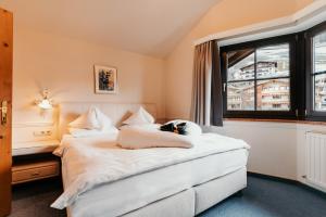 a bedroom with a white bed and a window at Dorfhotel Glücksschmiede in Saalbach-Hinterglemm