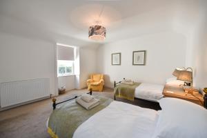 a bedroom with two beds and a chair at Longhill Farmhouse in Whithorn