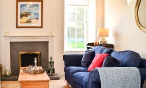a living room with a blue couch and a fireplace at Longhill Farmhouse in Whithorn