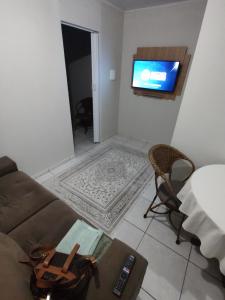 uma sala de estar com um sofá e uma TV de tela plana em Apartamento privativo 06 em Blumenau
