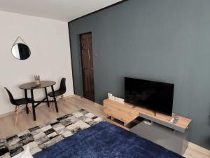 a living room with a flat screen tv and a table at Casa Rusu -Moroasa-Self check in-24h Netflix in Reşiţa