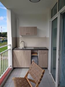 d'une cuisine avec un évier et une chaise sur un balcon. dans l'établissement Appartement dans résidence avec accès direct plage, à Folle Anse 4 autres photos