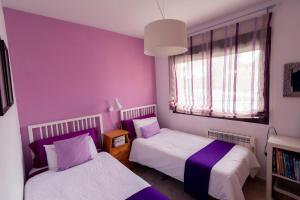 - 2 lits dans une chambre aux murs violets dans l'établissement Apartamento El Castillo, à La Adrada