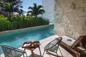 a patio with two chairs and a table next to a pool at Alea Tulum in Tulum