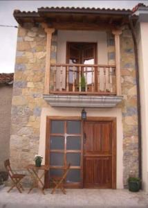 a building with a balcony and a wooden door at Casa rural La Casina in Sariego