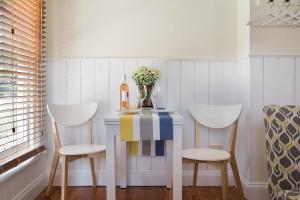 una mesa con dos sillas y un jarrón con flores. en Koovelly Garden Studio en Hepburn