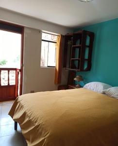1 dormitorio con cama y pared azul en Casa D´Maria, en Ollantaytambo