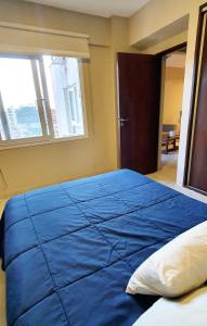 Cama grande azul en habitación con ventana en Balcarce 6 - Bon Repos en San Miguel de Tucumán