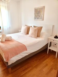1 dormitorio con 1 cama grande con sábanas y almohadas blancas en Apartamento Little Xoan, en Poio