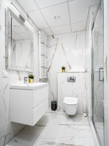 Baño blanco con lavabo y aseo en Warsaw Apartments Bliska Wola, en Varsovia