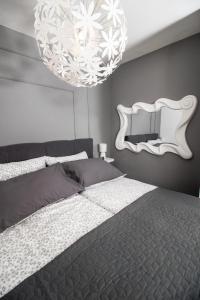 a bedroom with a bed with a mirror and a chandelier at Studio apartman Orhideja in Vinkovci