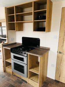 a kitchen with a stove and wooden cabinets at Kent Coast 3 bedroom holiday home in Rochester