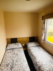 2 camas en una habitación pequeña con ventana en Kent Coast 3 bedroom holiday home, en Rochester
