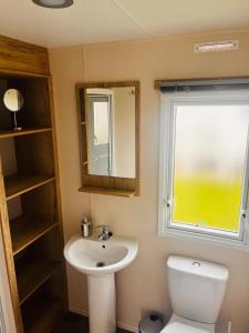 a bathroom with a sink and a toilet and a window at Kent Coast 3 bedroom holiday home in Rochester