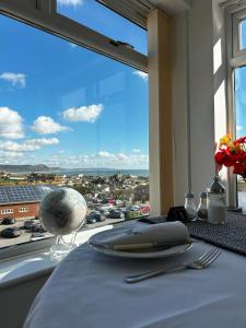 una mesa con un plato y una ventana con vistas. en Lucerne B&B en Lyme Regis