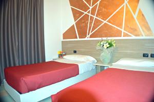 a room with two beds and a vase of flowers at Sempione Hotel Malpensa in Casorate Sempione