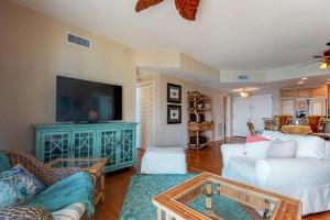 a living room with white furniture and a flat screen tv at Portofino 2-1906 in Pensacola Beach