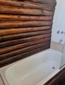 y baño con bañera y pared de madera. en Cabañas Qinti en San Pedro