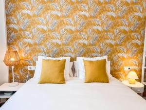 een bed met gele kussens in een slaapkamer met behang bij Tarifa Cozy House PALM BEACH in Tarifa