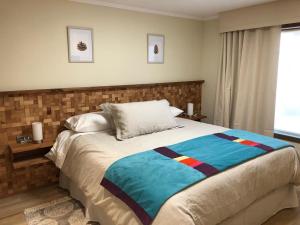Un dormitorio con una cama con una manta de colores. en Lodge Crux en Pichilemu