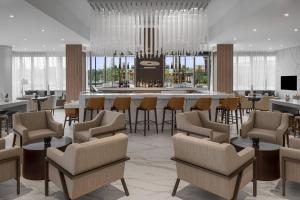 a lobby with a bar with chairs and a table at AC Hotel by Marriott Fort Lauderdale Sawgrass Mills Sunrise in Sunrise