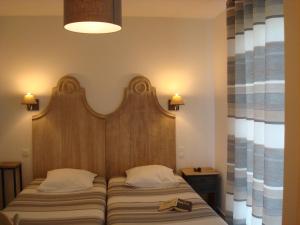 un letto con testiera in legno in una stanza di Chambres "Blanches" , bâtiment secondaire hotel la Caravelle, vue jardin a Biscarrosse-Plage