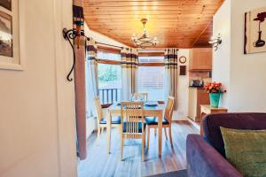 a dining room and living room with a table and chairs at Rustic Fawn Lodge with Hot Tub for 4 - Resort Spa in Devon in Chudleigh