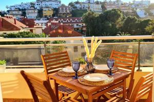 een houten tafel met stoelen en borden op een balkon bij Soleado apartamento Golf y a 900 m de la playa in Benalmádena