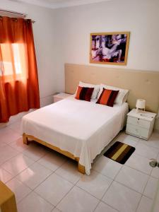 a bedroom with a large white bed with red curtains at IMOBITUR-Tourist Apartments- Palmarejo Centro AV SV in Praia