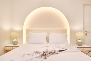 a white bed with a white headboard and flowers on it at Blush - Crema - Leopard Apartments in Zakynthos