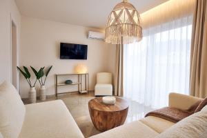 a living room with a couch and a table and a chandelier at Blush & Crema Apartments in Zakynthos