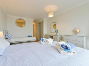Un dormitorio con una gran cama blanca con toallas. en 17 Burgh Island Causeway, en Kingsbridge 27 fotos más