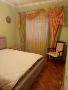 a bedroom with a bed and a chair and a window at Vila Arapovi - Bosilovo in Strumica