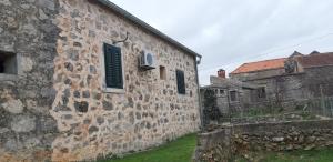 an old stone building with green shutters on it at Apartman Bogdan in Jelsa
