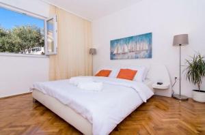 um quarto branco com uma cama grande e uma janela em Sunny place with sea view em Trogir