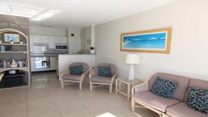 a living room with two chairs and a couch and a kitchen at Ebbtide 13 in Forster