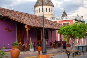 格拉納達的住宿－Hotel La Calzada，站在一座紫色建筑前面,有塔的男人