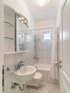 uma casa de banho branca com um lavatório e um WC em Apartments Villa Kapelica em Barbat na Rabu
