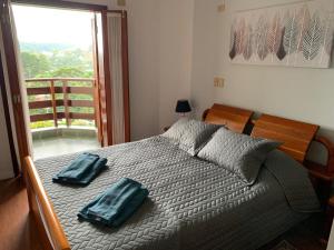 a bedroom with a bed with two blue pillows on it at Ed Belvedere Lindo Apto Capivari 190m2 in Campos do Jordão
