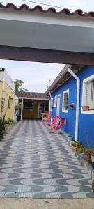 una casa con paredes azules y sillas rojas en un patio en Cantinho MurchioBom en Peruíbe