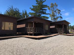 ein Haus mit zwei großen Holzhäusern mit einer Auffahrt in der Unterkunft Lodge Crux in Pichilemu