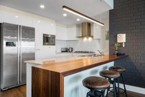 a kitchen with a wooden counter and a stainless steel refrigerator at Ocean View Spacious Luxury 3 Bedroom, Pool, Central, Walk everywhere 6PM CHECKOUT in The Entrance