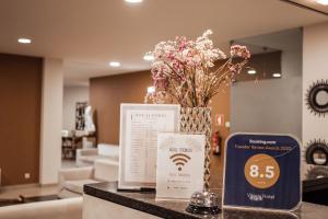 Vitoria Hotel في فاطمة: كاونتر توب مع إناء من الزهور وعلامة