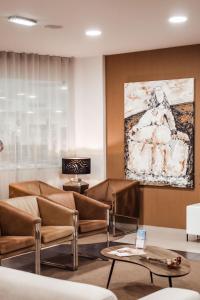 Vitoria Hotel في فاطمة: لوبي وكراسي جلديه ولوحه على الحائط